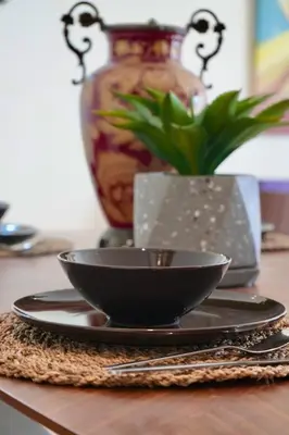 a black bowl on a plate on a table with a vase at Casablanca Finance City 2Bdr in Casablanca