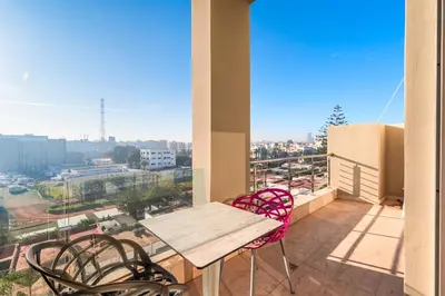 a balcony with a wooden table and chairs and a view at Urban Escape Designer Apartment with Balcony in Casablanca