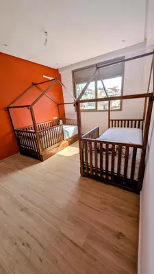 two beds in a room with orange walls and wooden floors at appartement en bord de mer Rabat in Rabat