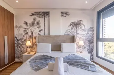 a bedroom with a large bed with palm trees wallpaper at Modern Studio in Maarif 16 with Free Private Parking in Casablanca