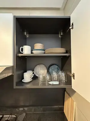 a cabinet with plates and cups and dishes on it at Hay Riad Sunset Studio Stadium View , 5 mind a pied stade moulay abdelah in Rabat