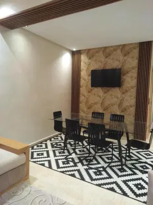 a dining room with a table and chairs on a rug at Beautiful apartment in Hay Al Qods Bernoussi in Casablanca