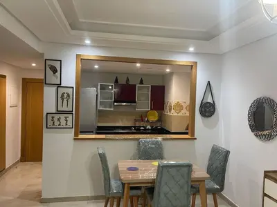 a dining room with a table and chairs and a kitchen at Lovely place in Casablanca