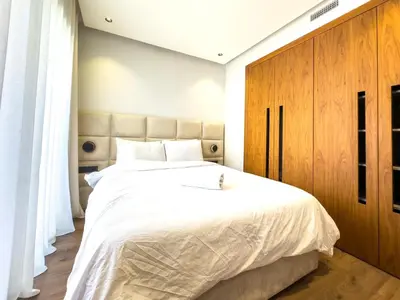 a bedroom with a large bed and a wooden cabinet at Modern, Fully Equipped Studio Just Steps from Mohammed 5 Stadium, Maarif in Casablanca