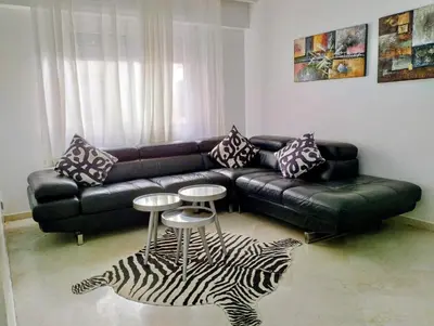 a living room with a black leather couch and a zebra rug at Appartament a 2 minute de la mer et la mosquee Hassan 2 in Casablanca-Port