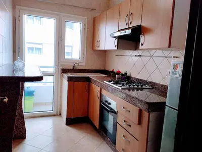 a kitchen with wooden cabinets and a stove top oven at Appartament a 2 minute de la mer et la mosquee Hassan 2 in Casablanca-Port
