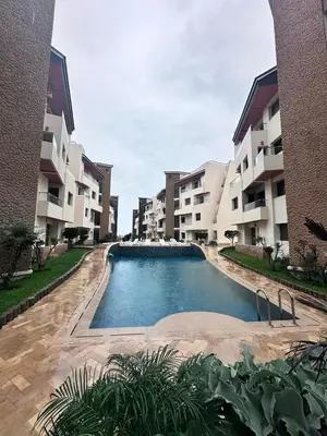 a swimming pool in front of some apartment buildings at Résidence Macha'allah in O Ben Slimane