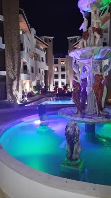 a fountain in the middle of a pool at night at Résidence Macha'allah in O Ben Slimane