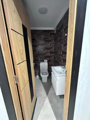a bathroom with a toilet and a sink and a door at Résidence Macha'allah in O Ben Slimane