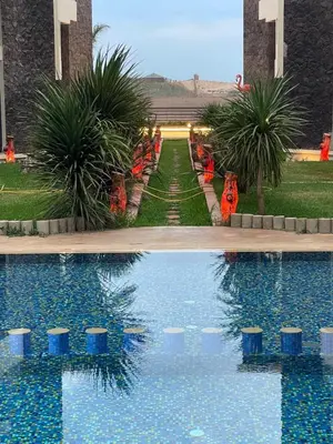 two pictures of a swimming pool with palm trees at Résidence Macha'allah in O Ben Slimane