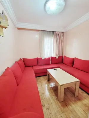 a red couch in a living room with a table at 7 min to beach luxury apartment Dar Bouazza in Casablanca
