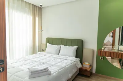 a bedroom with a large white bed with a green headboard at Peaceful Haven for a Quiet Stay in Maarif 500m to Mohamed Stadium in Casablanca