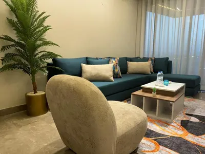 a living room with a blue couch and a palm tree at HERBA Studio - Cozy Space with an Unobstructed View in Bourgogne in Casablanca