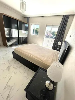 a bedroom with a bed and a table with a lamp at Villa Sophia in Dar Bouazza
