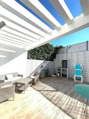 a patio with a wooden deck with chairs and a television at Villa Sophia in Dar Bouazza