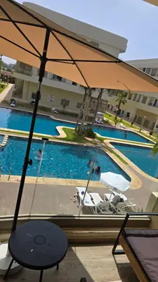 a table with an umbrella next to a swimming pool at appartement résidence garden paradise plage bouznika in Bouznika