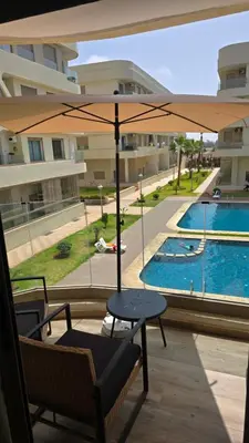 a patio with a table and an umbrella and a pool at appartement résidence garden paradise plage bouznika in Bouznika