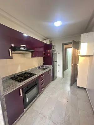 a kitchen with purple cabinets and a stove top oven at Appartement Marbella beach in Mansouria