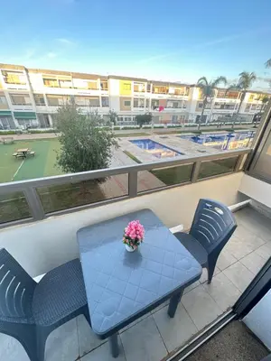 a table and chairs on a balcony with a tennis court at Appartement Marbella beach in Mansouria