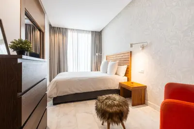 a hotel room with a bed and a red chair at APGCI-Elegant studio sur Ferme bretonne in Casablanca
