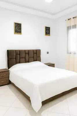a bedroom with a large white bed with a brown headboard at Évasion Marine & piscine 3 chambres in Bouznika