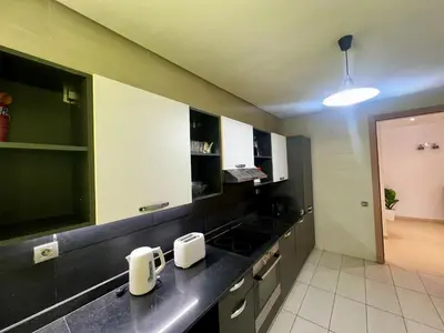 a kitchen with black counter tops and white cabinets at Urban Chic 2BR - Prestigia near stadium in Rabat