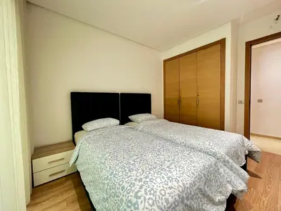 a bedroom with a large bed and a wooden closet at Urban Chic 2BR - Prestigia near stadium in Rabat