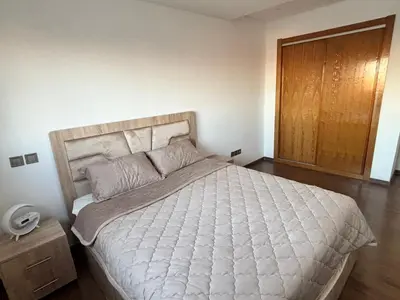 a bedroom with a large white bed with a wooden headboard at Appartement moderne aux perles de temara in Temara