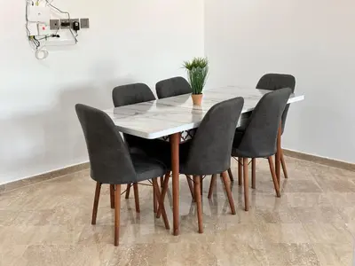 a dining room table with four chairs and a plant on it at Appartement moderne aux perles de temara in Temara