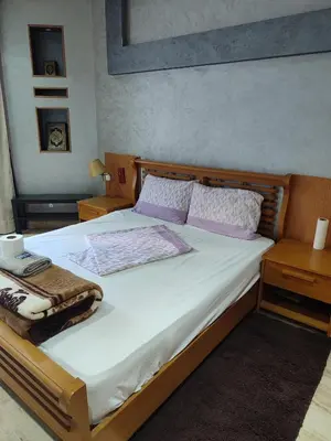 a bedroom with a bed with white sheets and purple pillows at Grande appartement 4 chambre in Casablanca