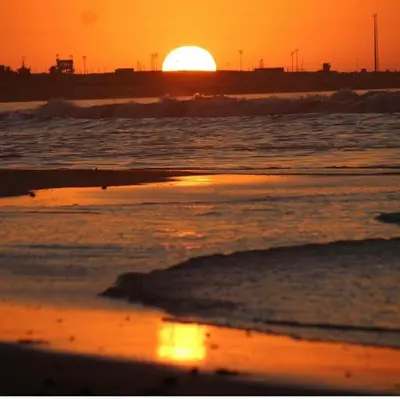 a sunset on the beach with the sun setting at Métropole parc Manesmane in Mohammedia