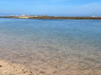 a body of water with a sandy beach and buildings at Métropole parc Manesmane in Mohammedia