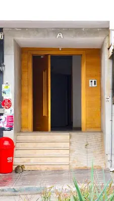 a wooden door of a building with a red bucket at Modern Apt with sea view and access to the beach in El Harhoura