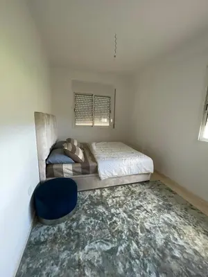 a small bedroom with a bed and a blue chair at Appartement à Skhirat plage in Skhirat