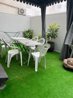 a patio with a table and chairs on green grass at Joli Appartement 2 pièces in Rabat
