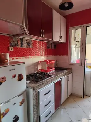 a kitchen with red walls and a stove top oven at Eco Gare centre 2 chambres in Bouznika