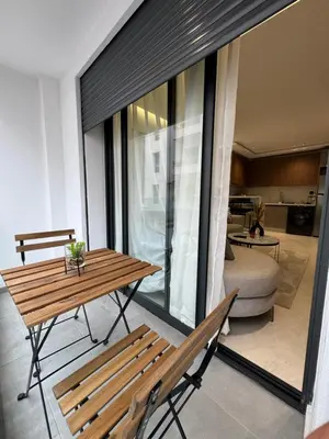 a balcony with a wooden table and benches and a living room at Studio à louer in Casablanca