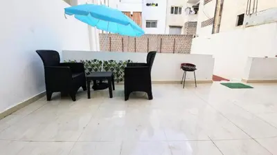 a table and chairs with a blue umbrella on a balcony at Central Cosy studio steps to Shore in Rabat