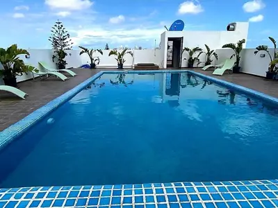 a large blue swimming pool with chairs and a building at Cozy private jacuzzi spa apartment in Casablanca