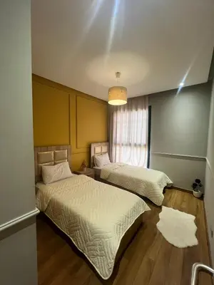 two beds in a room with a window at Appartement dans un cadre convivial in Rabat