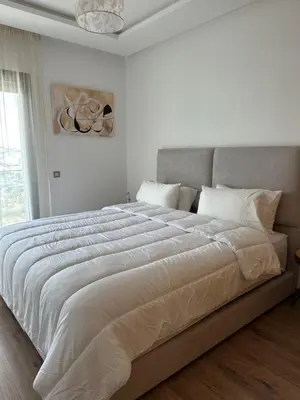 a white bedroom with a large bed with white sheets at Cosy Appartement in Rabat