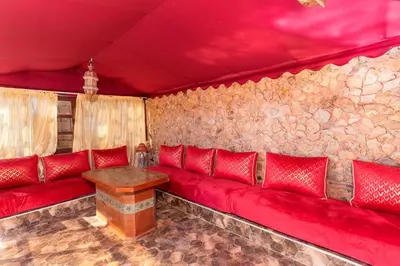 a red couch in a room with a stone wall at La Tulipe de Zaer - Maison de Campagne vue Montagnes - Piscine Privée