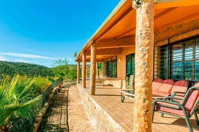 a porch of a house with chairs on it at La Tulipe de Zaer - Maison de Campagne vue Montagnes - Piscine Privée