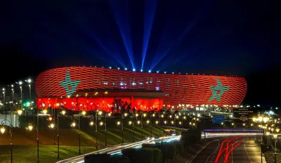 a building lit up with red and blue lights at night at Appartement Bouznika POOL & BEACH in Bouznika