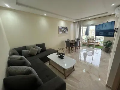 a living room with a couch and a table at Appartement Bouznika POOL & BEACH in Bouznika