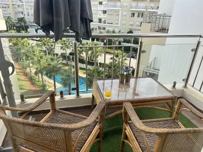 a balcony with a table and chairs and a view of a pool at Appartement Bouznika POOL & BEACH in Bouznika