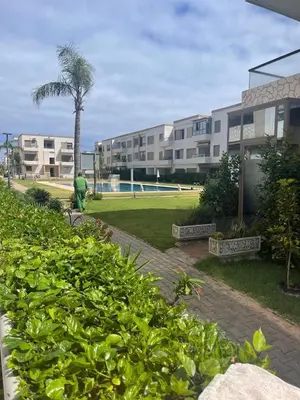 a park with a palm tree and a building at Apartment with piscine in Mansouria