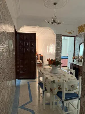 a dining room with a table and chairs with a vase on it at Appartement central à Témara, proche de Rabat in Temara