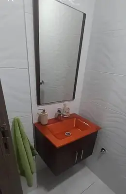 a bathroom with a red sink and a mirror at well-equipped apartment in Mansouria