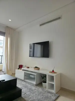 a white living room with a tv on a wall at super studio in Aïn Harrouda